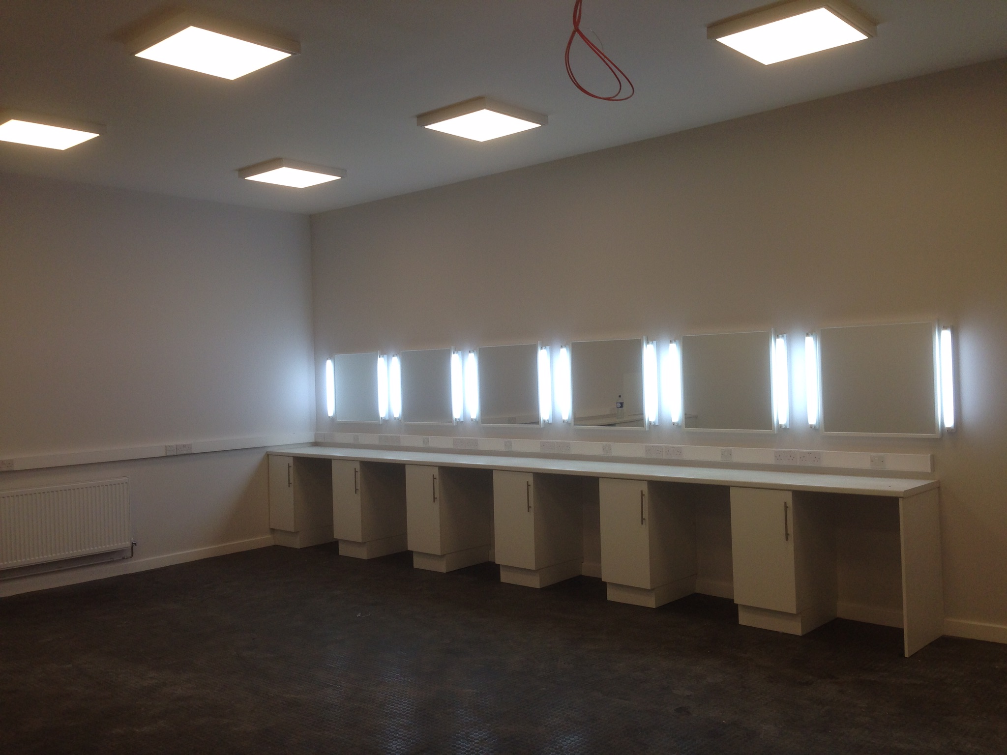 Brightly lit room with ceiling panels, illuminated mirrors and work surfaces