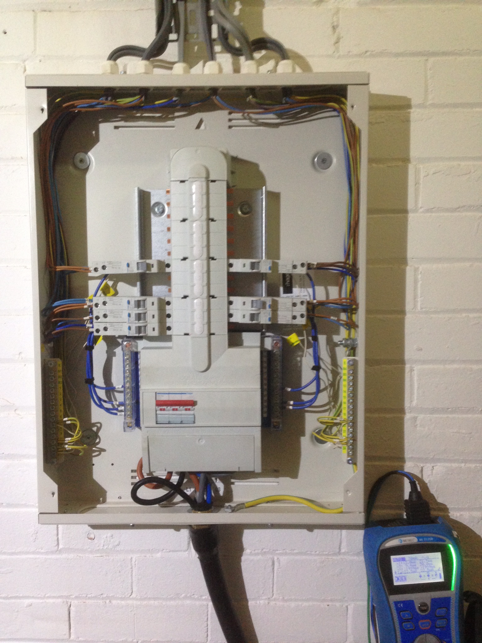 Open distribution board with an electrical testing instrument alongside