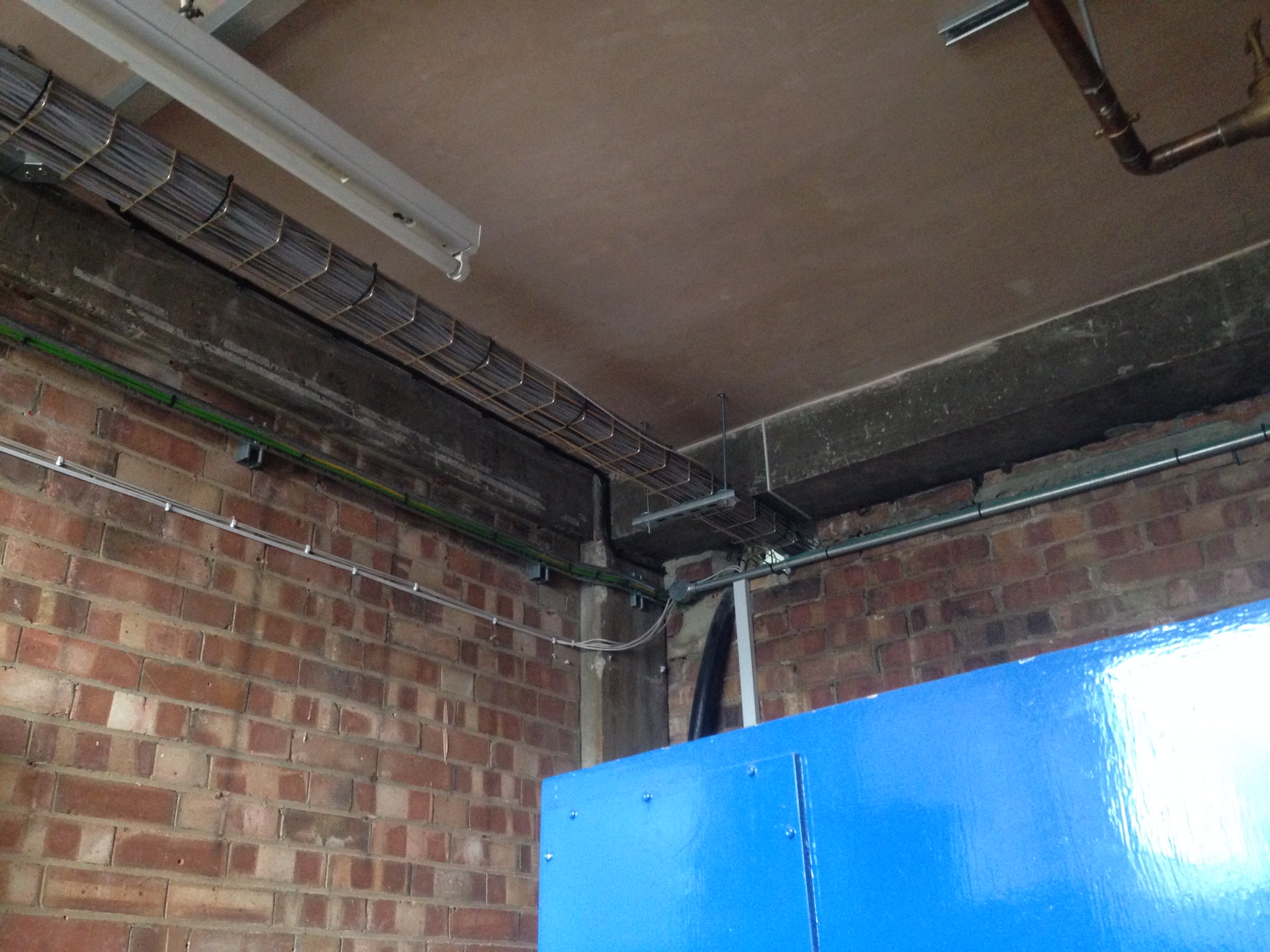 Electrical cables and metal containment in a brick-walled work area